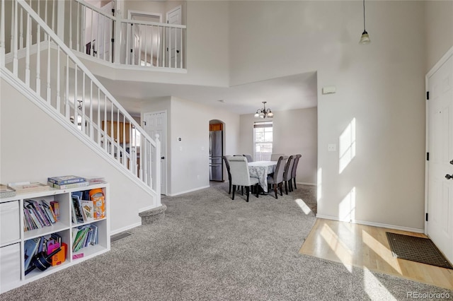 carpeted foyer with a high ceiling and an inviting chandelier