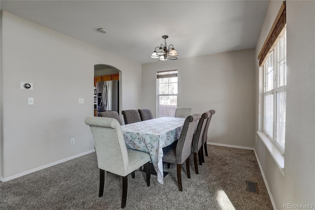 dining area featuring dark colored carpet and a notable chandelier