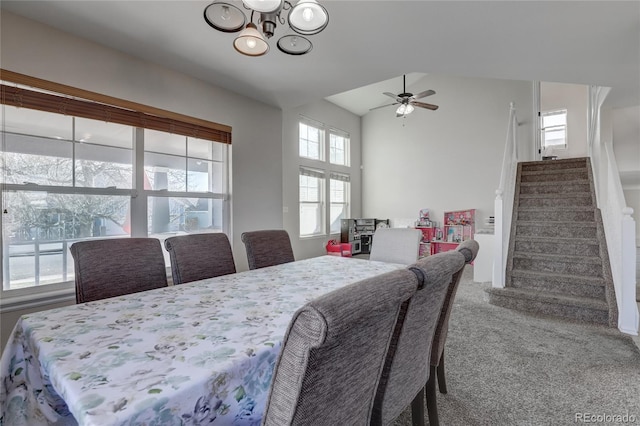 dining area featuring vaulted ceiling, carpet floors, and ceiling fan with notable chandelier