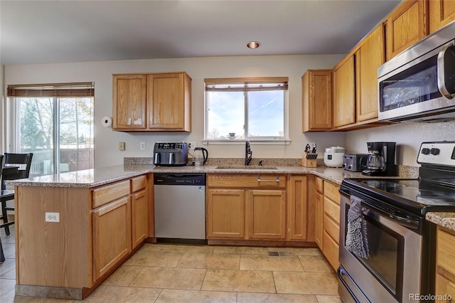 kitchen featuring light stone countertops, sink, kitchen peninsula, and stainless steel appliances