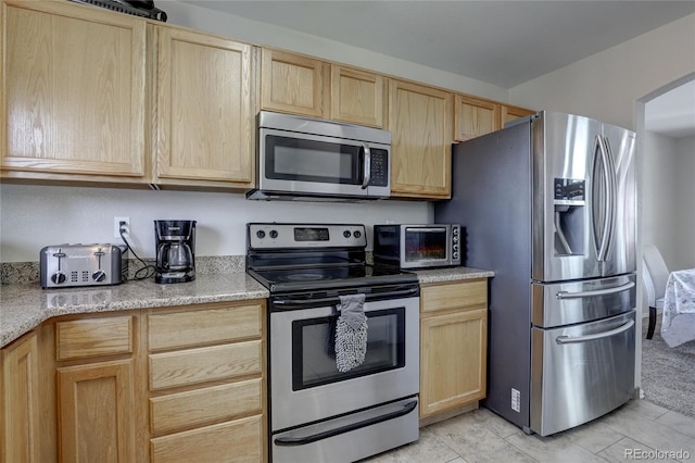 kitchen with light tile patterned floors, stainless steel appliances, and light brown cabinetry