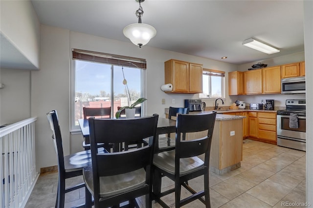 kitchen with appliances with stainless steel finishes, light brown cabinets, and decorative light fixtures