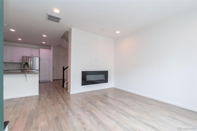 15443 W 65th Ave Unit B, Arvada, CO 80007 - unfurnished living room featuring light wood-style flooring, recessed lighting, and a glass covered fireplace