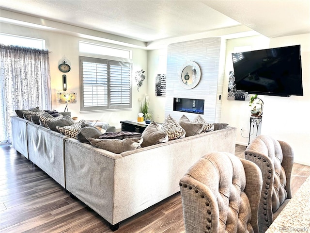 living area featuring a textured ceiling, a large fireplace, and dark wood-style flooring