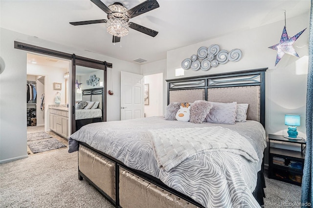 bedroom with baseboards, carpet floors, ceiling fan, ensuite bathroom, and a barn door