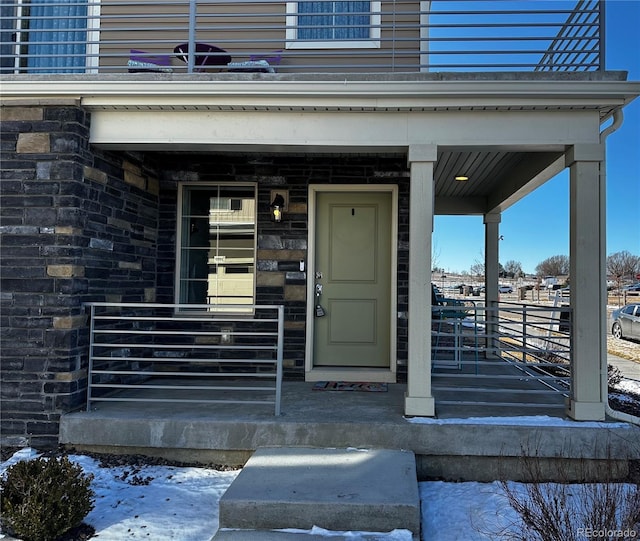 property entrance with a porch and stone siding