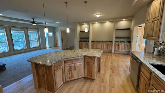 kitchen with decorative light fixtures, stainless steel dishwasher, ceiling fan, and a kitchen island