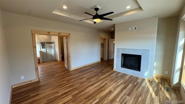 unfurnished living room featuring baseboards, a tray ceiling, wood finished floors, and visible vents