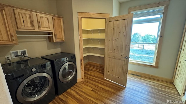 clothes washing area with cabinets, independent washer and dryer, and light hardwood / wood-style floors