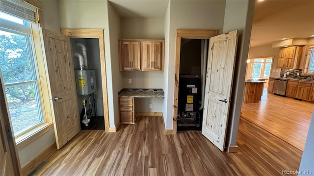 kitchen featuring stainless steel dishwasher, sink, hardwood / wood-style floors, and water heater