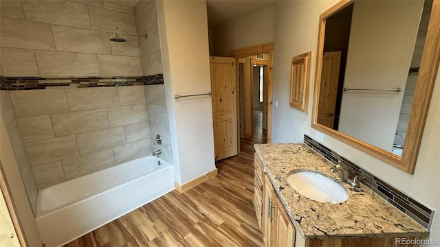 bathroom with wood-type flooring, tiled shower / bath combo, and vanity