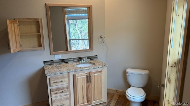 bathroom with vanity, baseboards, toilet, and wood finished floors