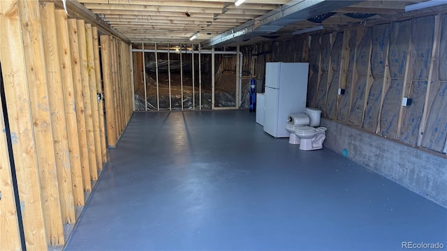 basement with water heater and white refrigerator