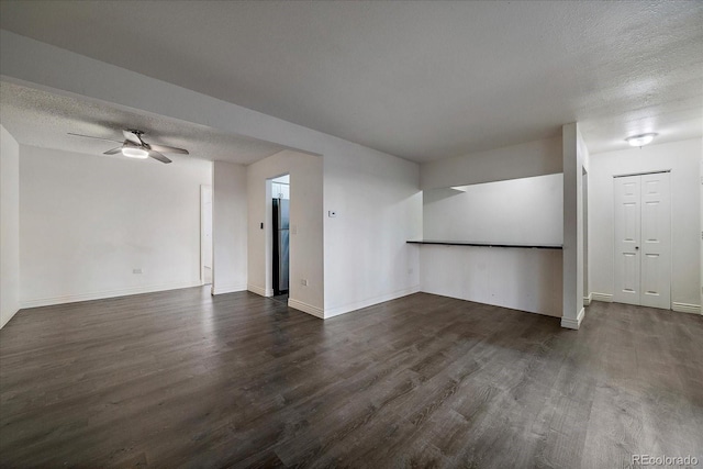 spare room featuring a textured ceiling, dark wood finished floors, a ceiling fan, and baseboards