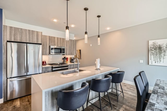 930 Blue River Pkwy Unit 812, Silverthorne, CO 80498 - kitchen with brown cabinetry, a kitchen breakfast bar, a sink, dark wood finished floors, and stainless steel appliances