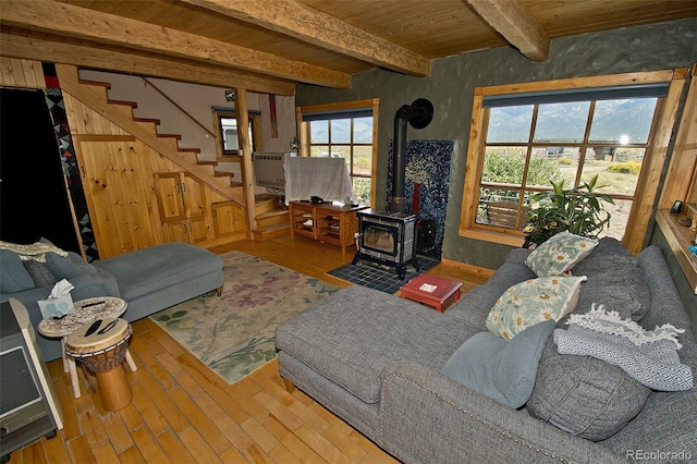 living room featuring hardwood / wood-style flooring, a wood stove, beamed ceiling, and wooden ceiling