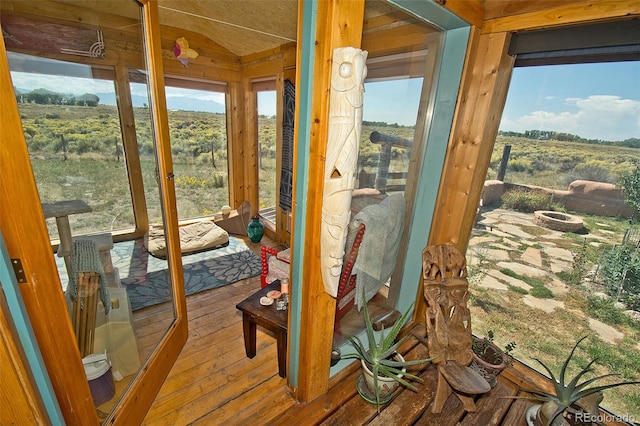 sunroom / solarium featuring vaulted ceiling, a wealth of natural light, and a rural view