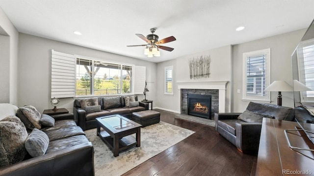 living room with dark wood-type flooring, ceiling fan, and a fireplace