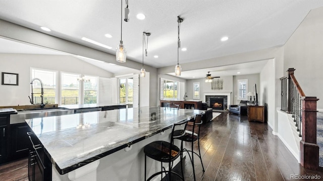 kitchen with sink, a breakfast bar area, dark hardwood / wood-style floors, pendant lighting, and a large island