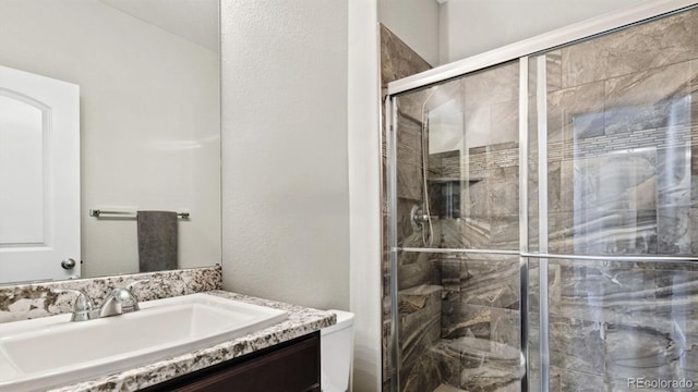 bathroom with a shower with door, vanity, and toilet