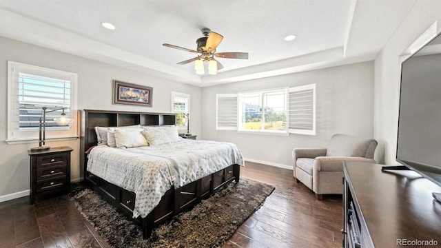 bedroom featuring dark hardwood / wood-style flooring, a raised ceiling, and ceiling fan