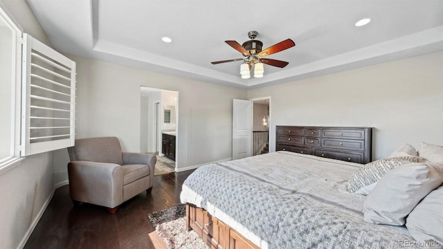 bedroom with dark hardwood / wood-style floors, a raised ceiling, ceiling fan, and ensuite bathroom