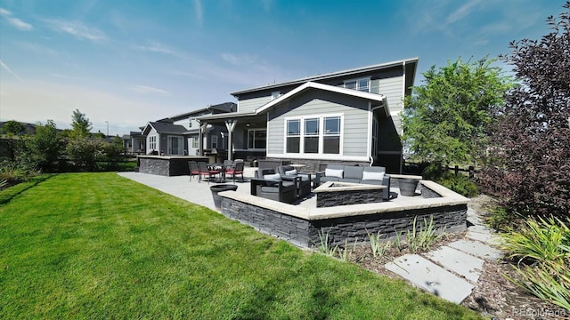 rear view of property with a yard, a patio, and an outdoor living space with a fire pit