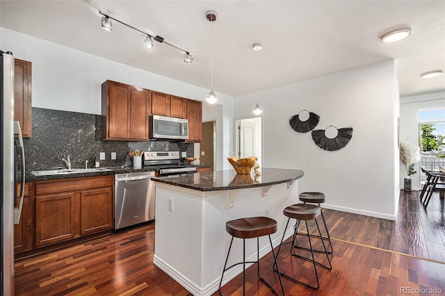 10184 Park Meadows Dr Unit 1102, Lone Tree, CO 80124 - kitchen featuring appliances with stainless steel finishes, brown cabinetry, dark wood finished floors, tasteful backsplash, and a sink