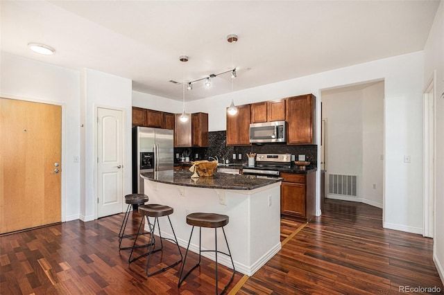10184 Park Meadows Dr Unit 1102, Lone Tree, CO 80124 - kitchen featuring appliances with stainless steel finishes, a breakfast bar area, dark wood-type flooring, and backsplash