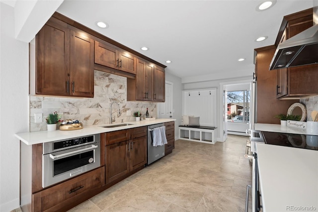 kitchen with appliances with stainless steel finishes, sink, backsplash, and exhaust hood