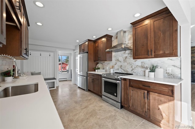 kitchen with backsplash, stainless steel appliances, wall chimney exhaust hood, and sink