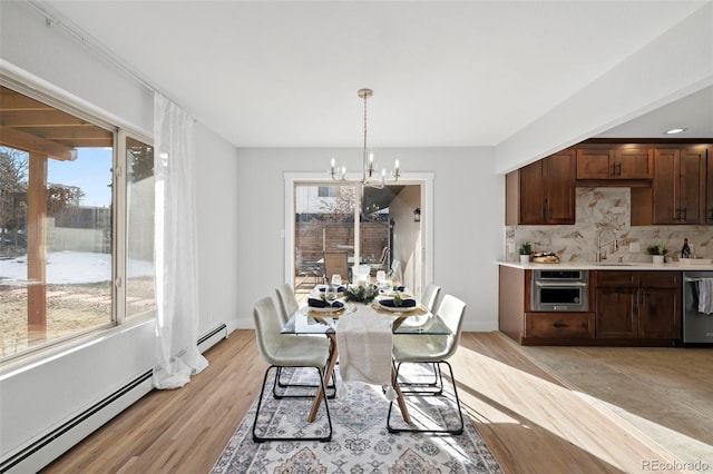 dining area with baseboard heating, a wealth of natural light, sink, and a notable chandelier