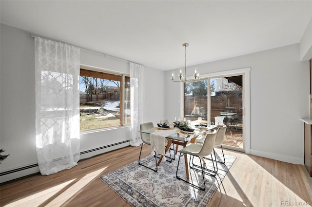 dining room with light wood-type flooring, a baseboard radiator, and an inviting chandelier