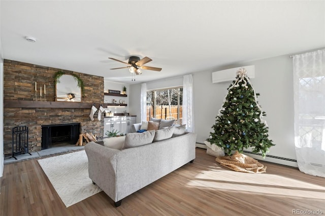 living room featuring ceiling fan, a fireplace, wood-type flooring, and a wall mounted air conditioner