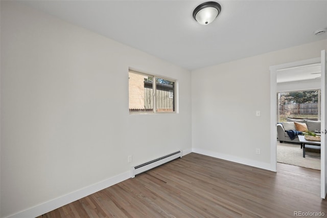 unfurnished room featuring wood-type flooring and a baseboard radiator