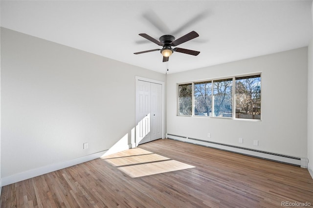 spare room featuring wood-type flooring, a baseboard radiator, and ceiling fan