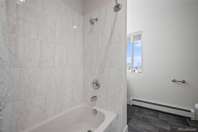 bathroom with baseboard heating, toilet, and tiled shower / bath