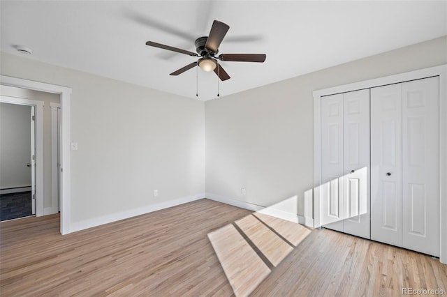 unfurnished bedroom with ceiling fan, a closet, light hardwood / wood-style floors, and a baseboard heating unit