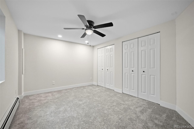 unfurnished bedroom with ceiling fan, two closets, light colored carpet, and a baseboard heating unit