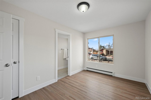 unfurnished bedroom with connected bathroom, a baseboard radiator, light hardwood / wood-style flooring, and a closet