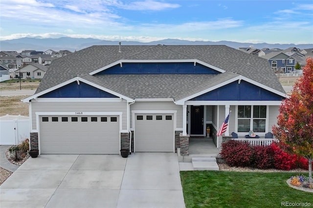 view of front of house featuring a mountain view, a garage, a front lawn, and a porch