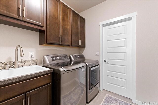 washroom featuring cabinets, washing machine and dryer, light tile patterned flooring, and sink