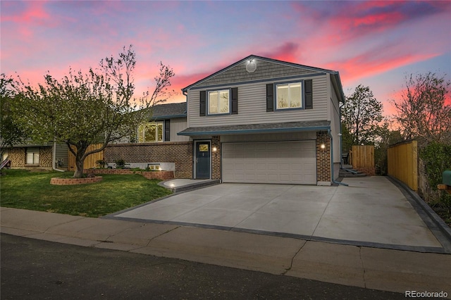 tri-level home featuring a lawn, a garage, brick siding, fence, and concrete driveway