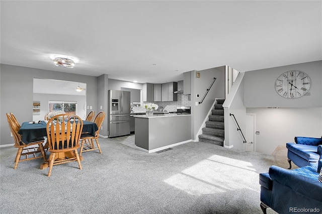 dining area with a ceiling fan, visible vents, baseboards, light carpet, and stairs
