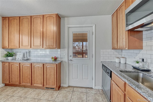 kitchen featuring a sink, backsplash, stainless steel appliances, light tile patterned floors, and light stone countertops