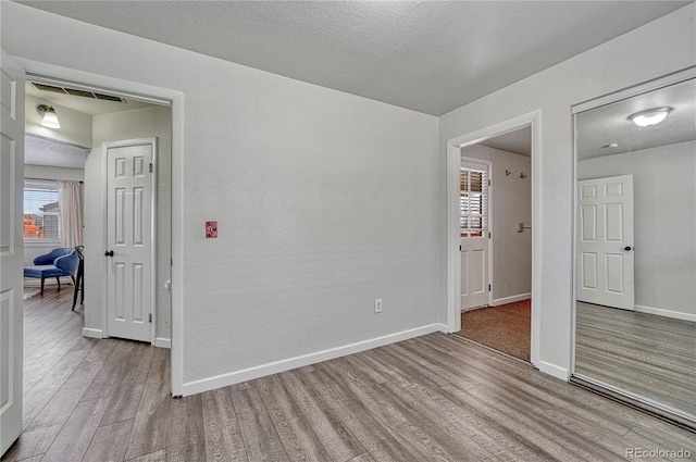 empty room featuring visible vents, baseboards, a textured ceiling, and wood finished floors