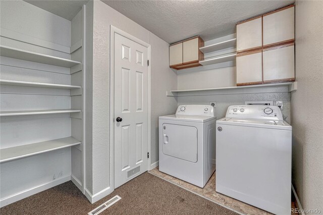 laundry room with a textured ceiling, cabinet space, visible vents, and washer and clothes dryer