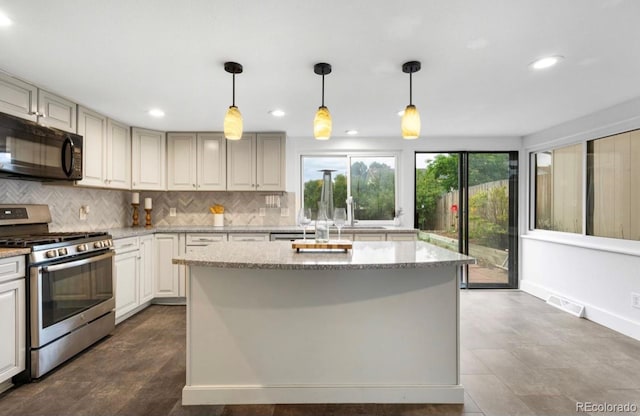 kitchen featuring gas stove, light stone countertops, and pendant lighting