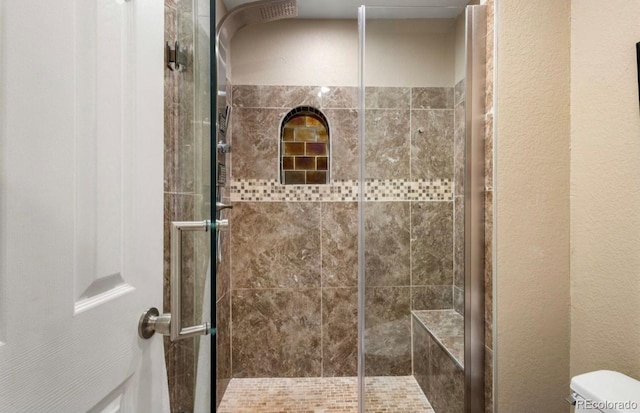 bathroom with a shower with shower door and toilet