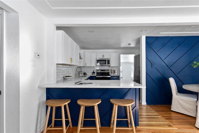 kitchen with white cabinets, a breakfast bar, appliances with stainless steel finishes, and light countertops